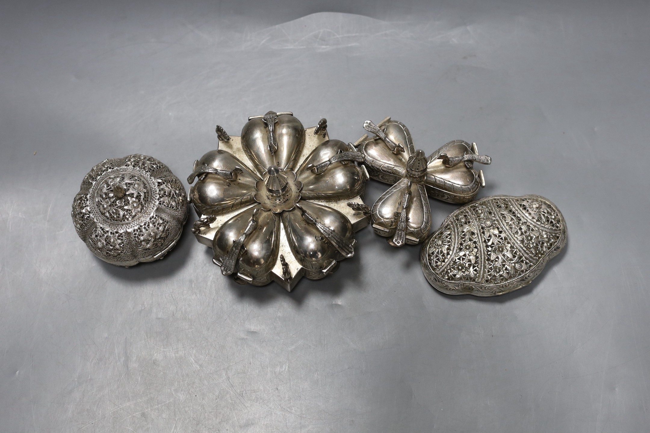 Two 20th century Indian white metal segmental spice boxes, decorated with peacocks, largest 13.5cm and two similar pierced scent boxes with covers.